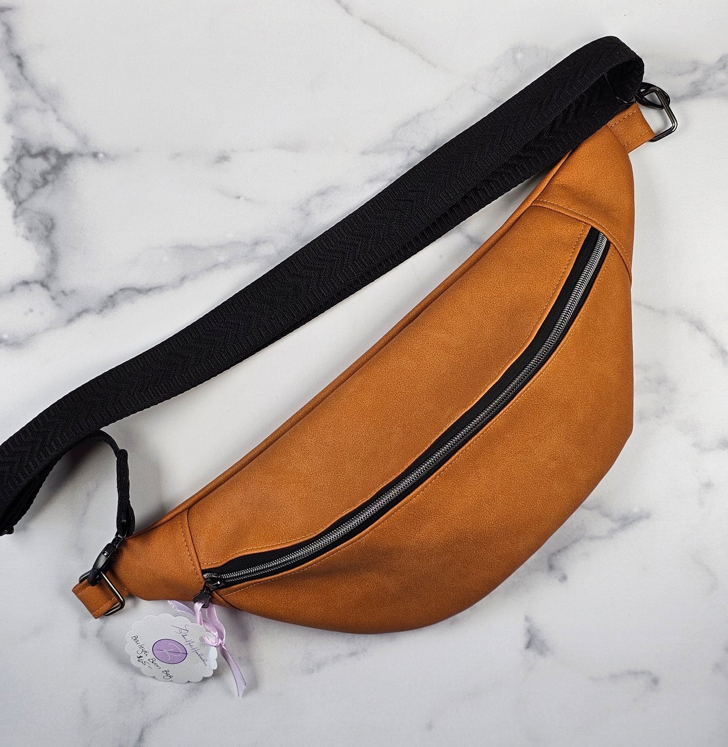 Tan faux leather bum bag, sling bag with fun cat ug cotton lining, black textured strap, with interior zippered and slip pockets.