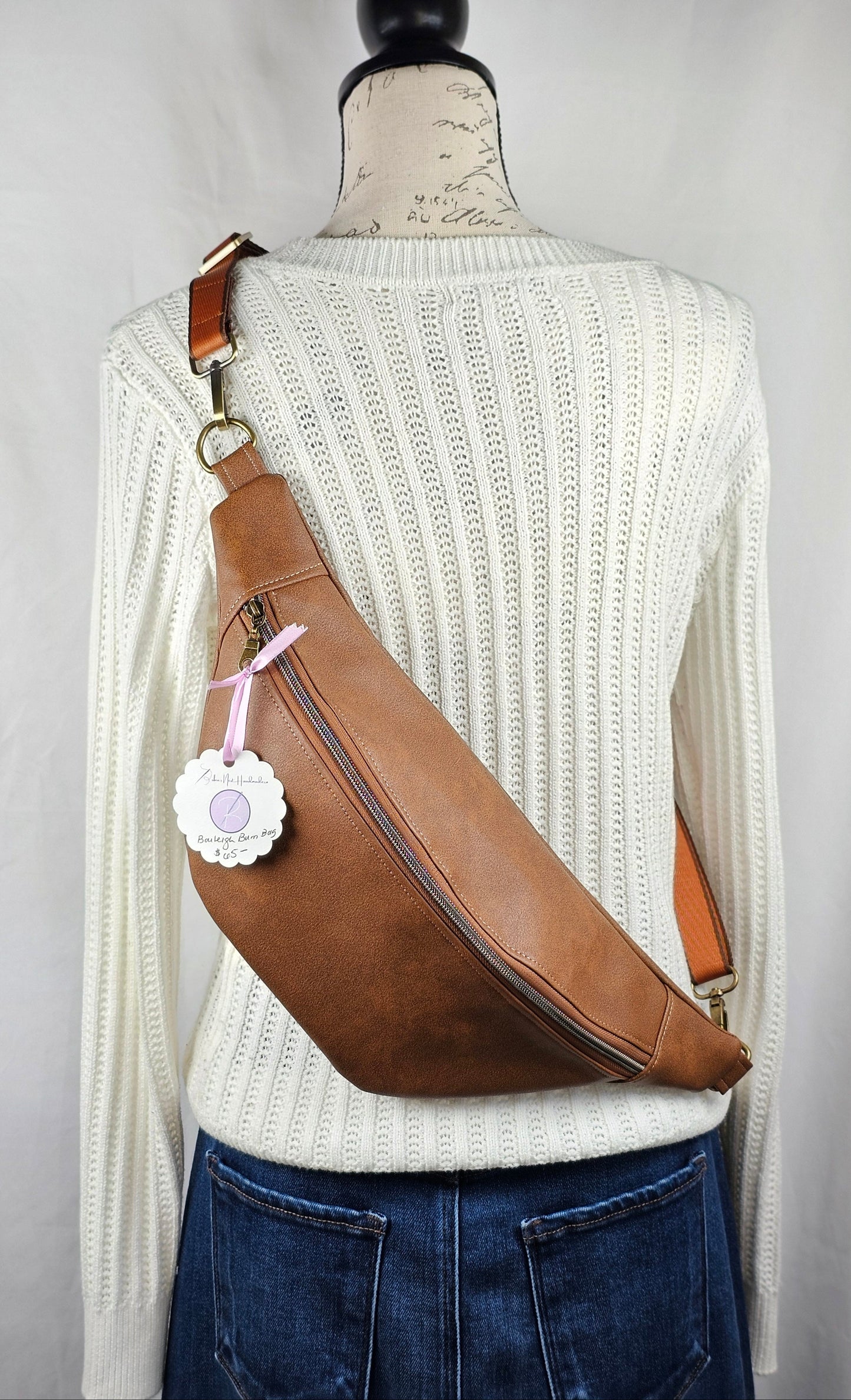 Brown faux leather bag with brown mushroom cotton interior.  Brown one inch adjustable strap with antique brass hardware. One zippered interior pocket and one slip interior pocket.