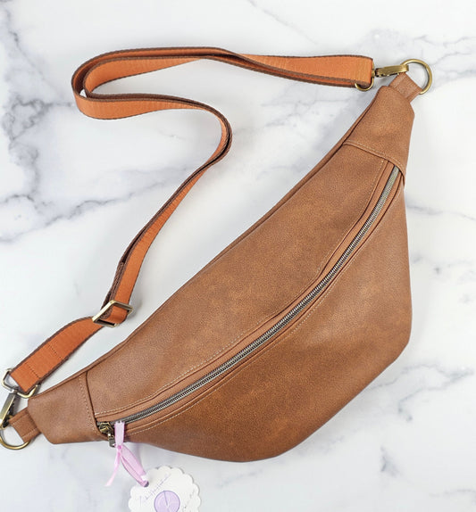 Brown faux leather pouch bag with mushroom cotton interior fabric and one zippered interior pocket and one slip pocket. Antique brass hardware