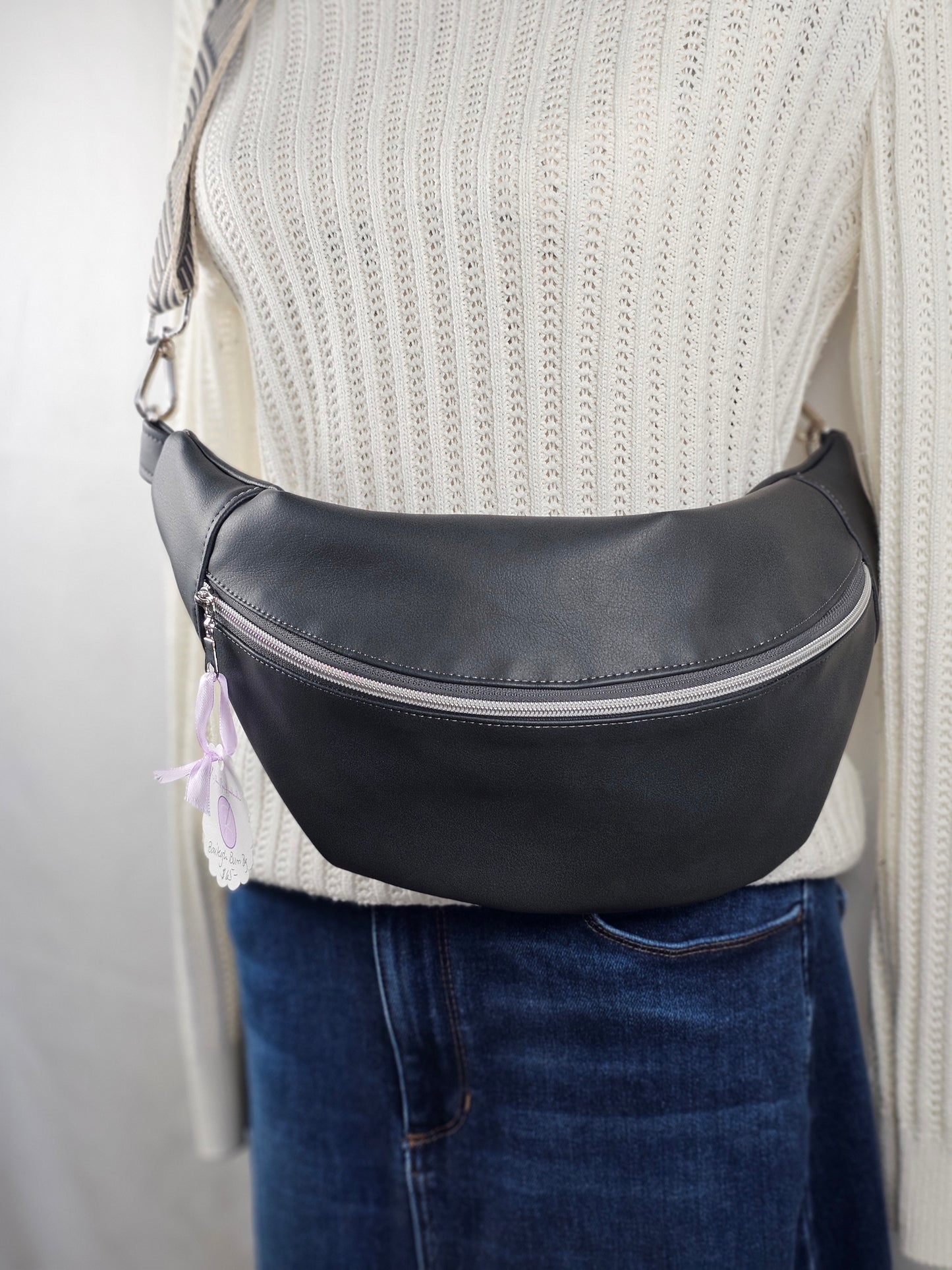Dark gray sling bag with striped grey and white strap and a gray mushroom cotton canvas interior fabric. One interior slip pocket