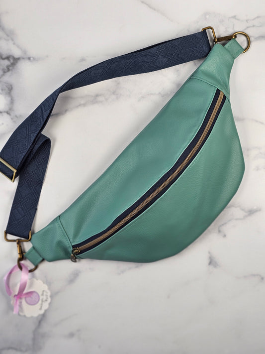 Green sling bag with a blue strap on a marble surface