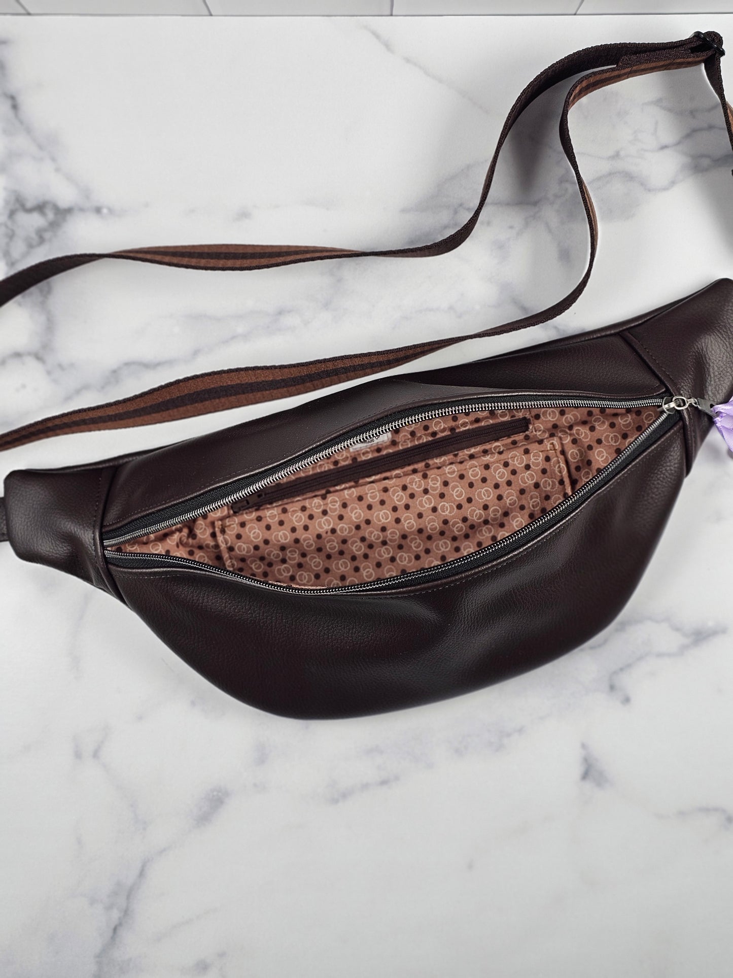 Brown faux leather bag with polka dot interior on a marble surface