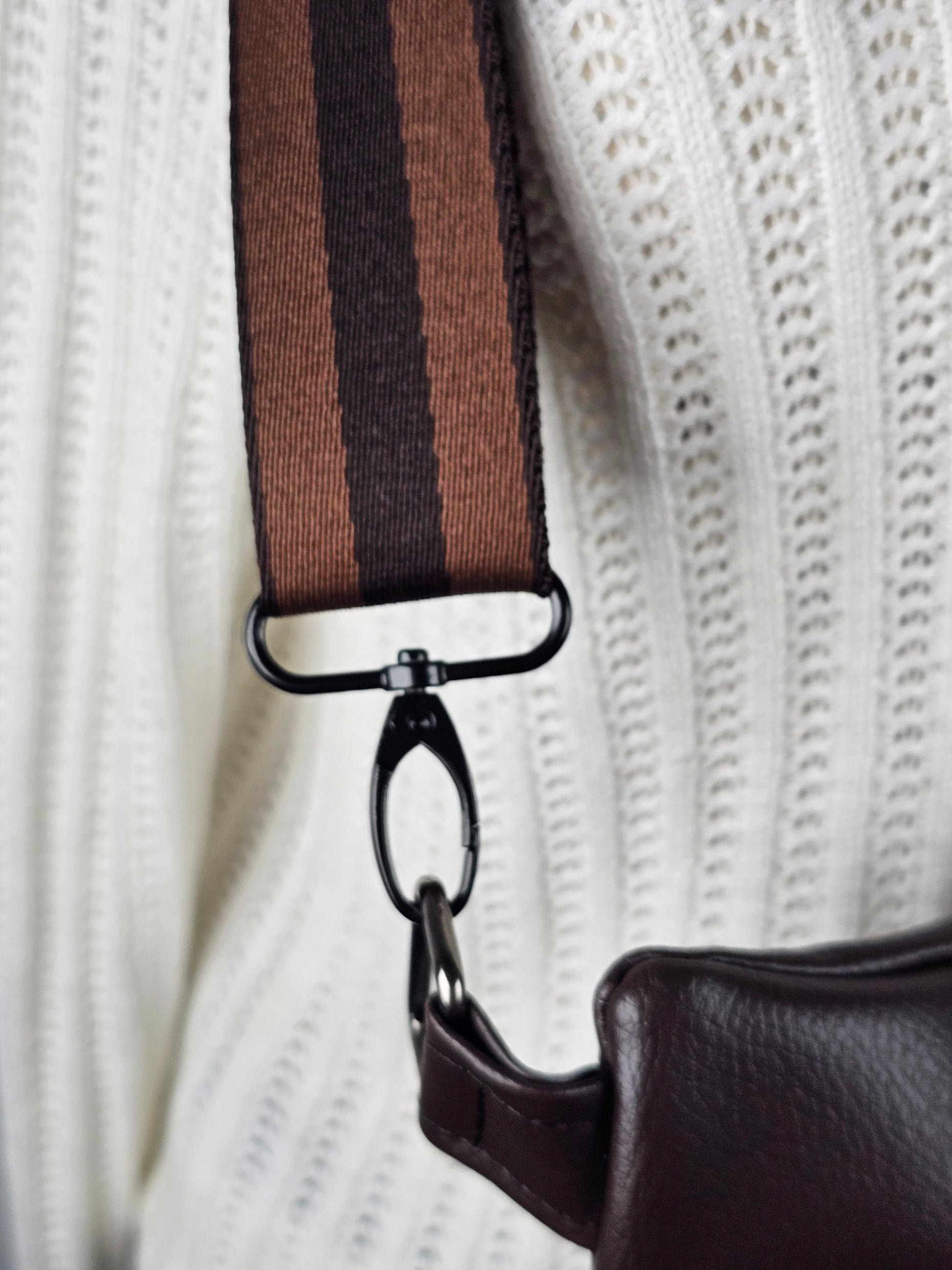 Brown faux leather bag with a strap on a white textured background