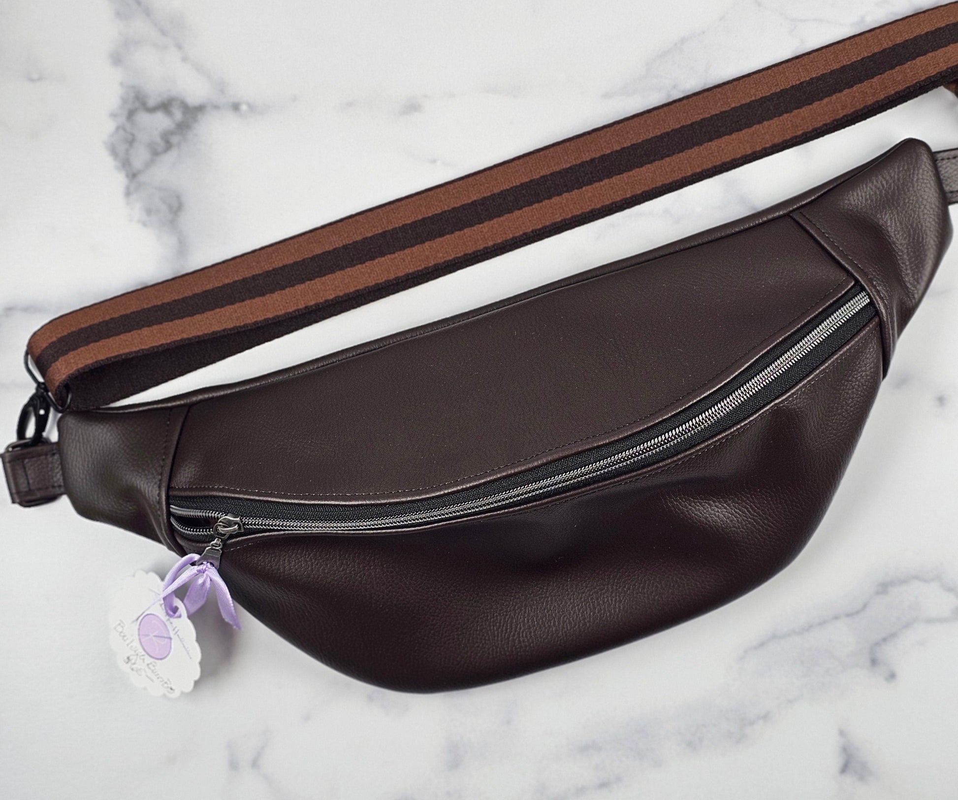 Brown faux leather sling bag on a marble surface