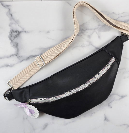 Dark gray faux leather sling fanny pack with gray leopard print zipper and light gray chevron strap. Interior gray floral with interior zip and slip pockets.