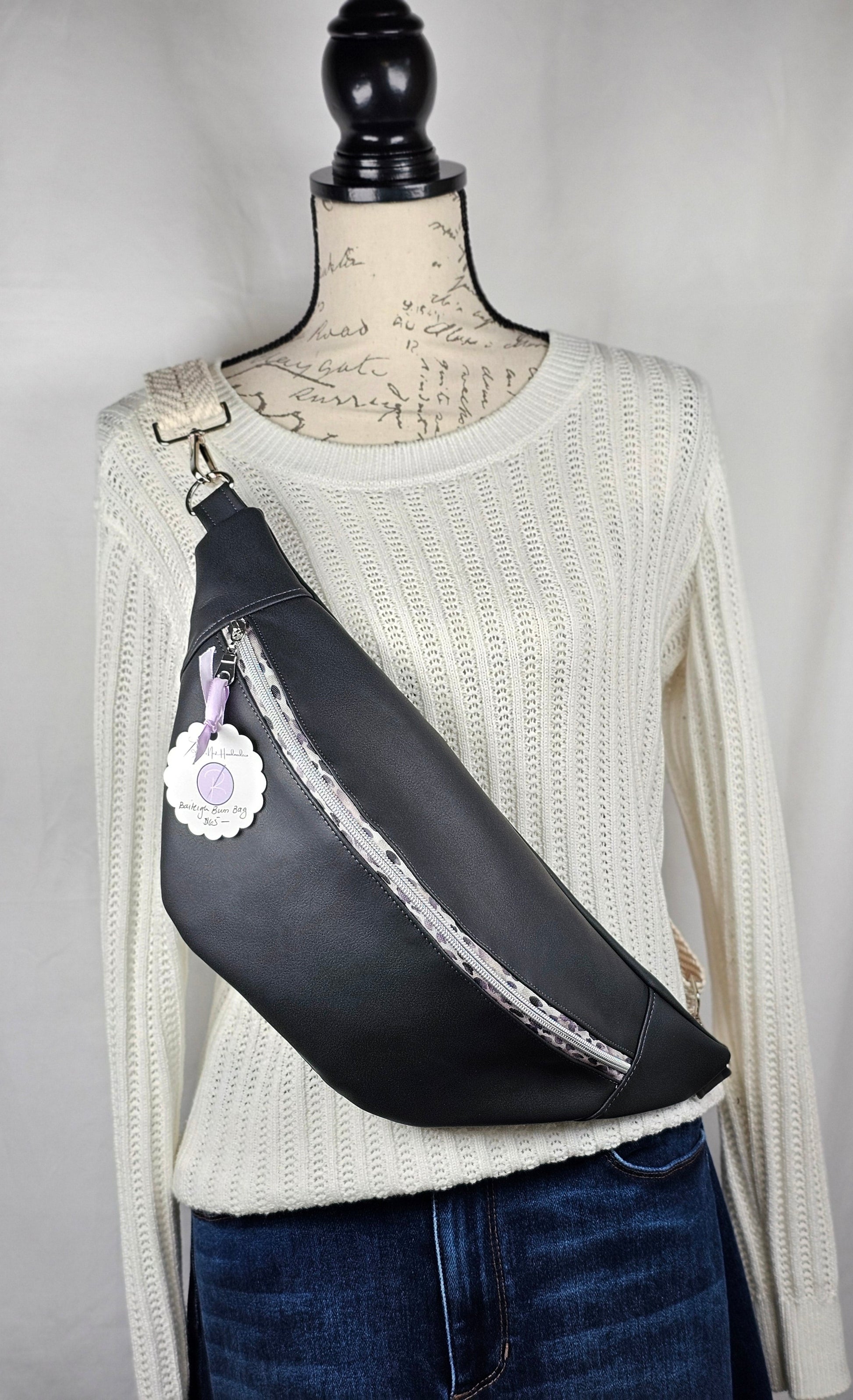 Dark gray faux leather sling fanny pack with gray leopard print zipper and light gray chevron strap. Interior gray floral with interior zip and slip pockets.