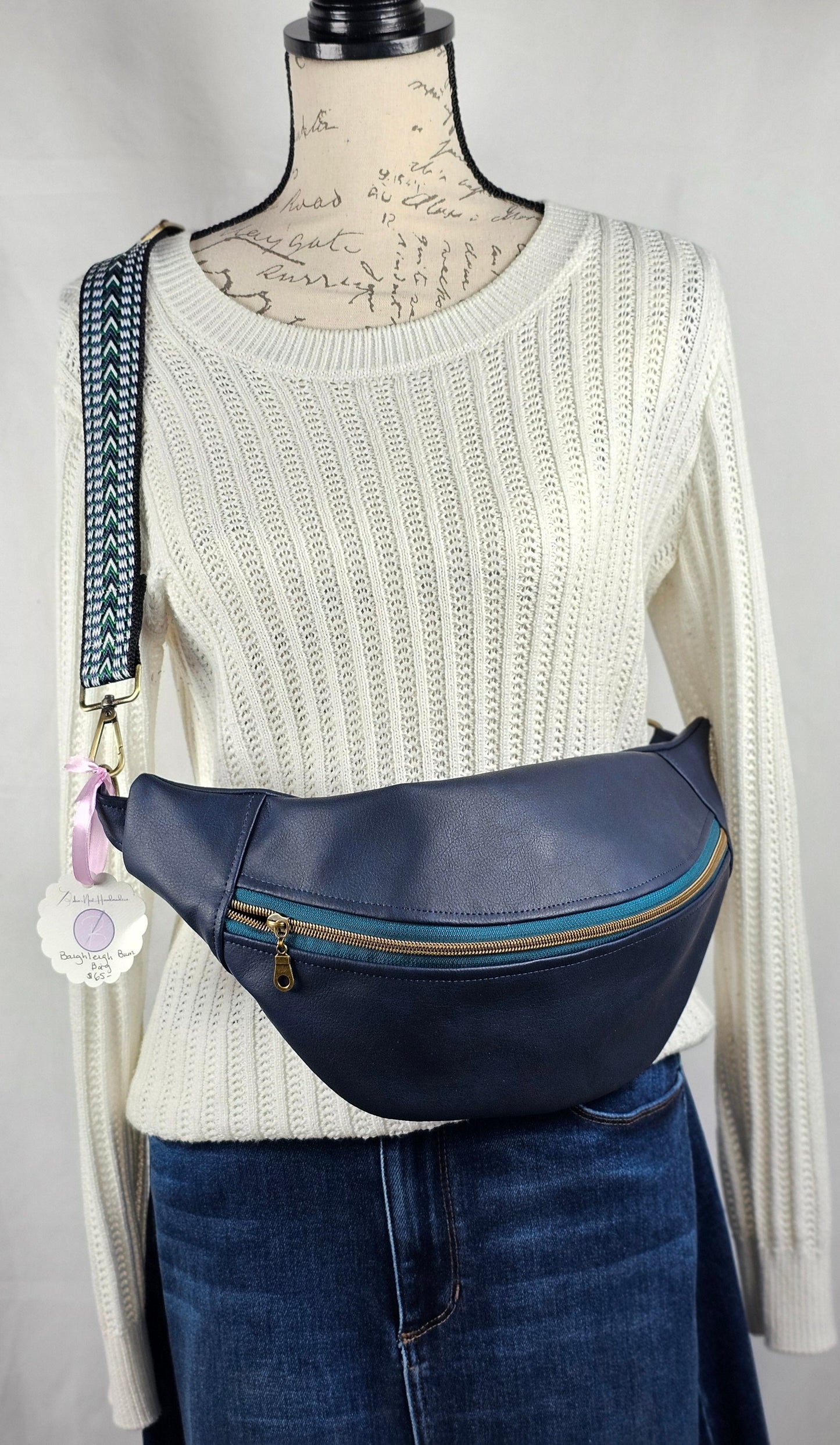 navy faux leather sling bag with multicolored strap and navy floral interior cotton lining with one zippered pocket and one slip pocket.