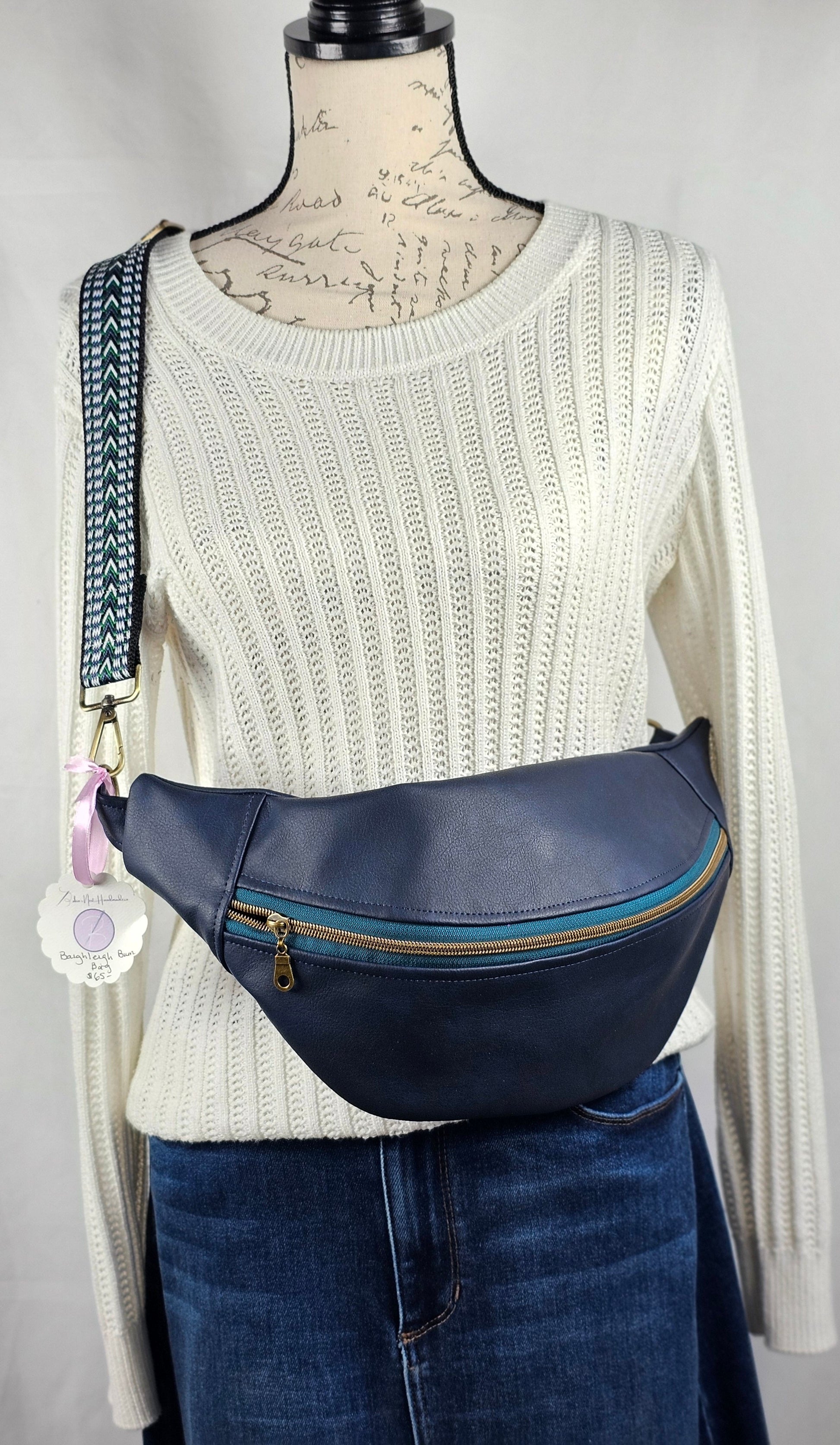 navy faux leather sling bag with multicolored strap and navy floral interior cotton lining with one zippered pocket and one slip pocket.