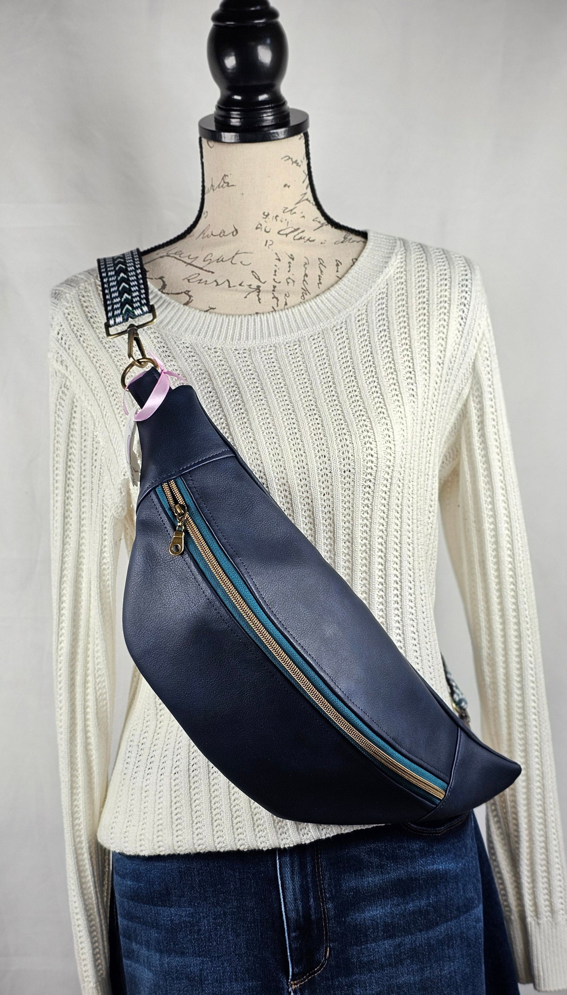 navy faux leather sling bag with multicolored strap and navy floral interior cotton lining with one zippered pocket and one slip pocket.