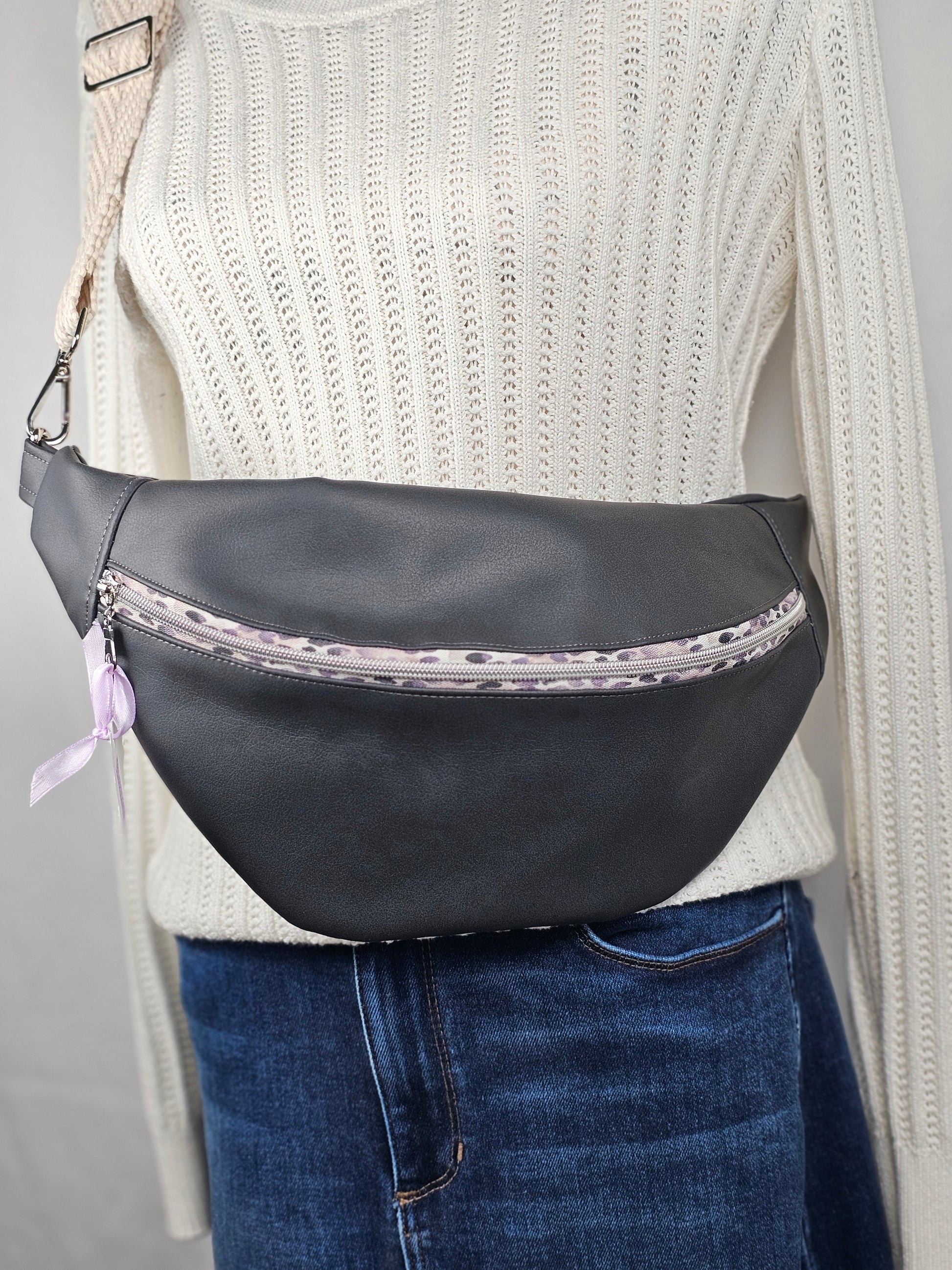 Dark gray faux leather sling fanny pack with gray leopard print zipper and light gray chevron strap. Interior gray floral with interior zip and slip pockets.