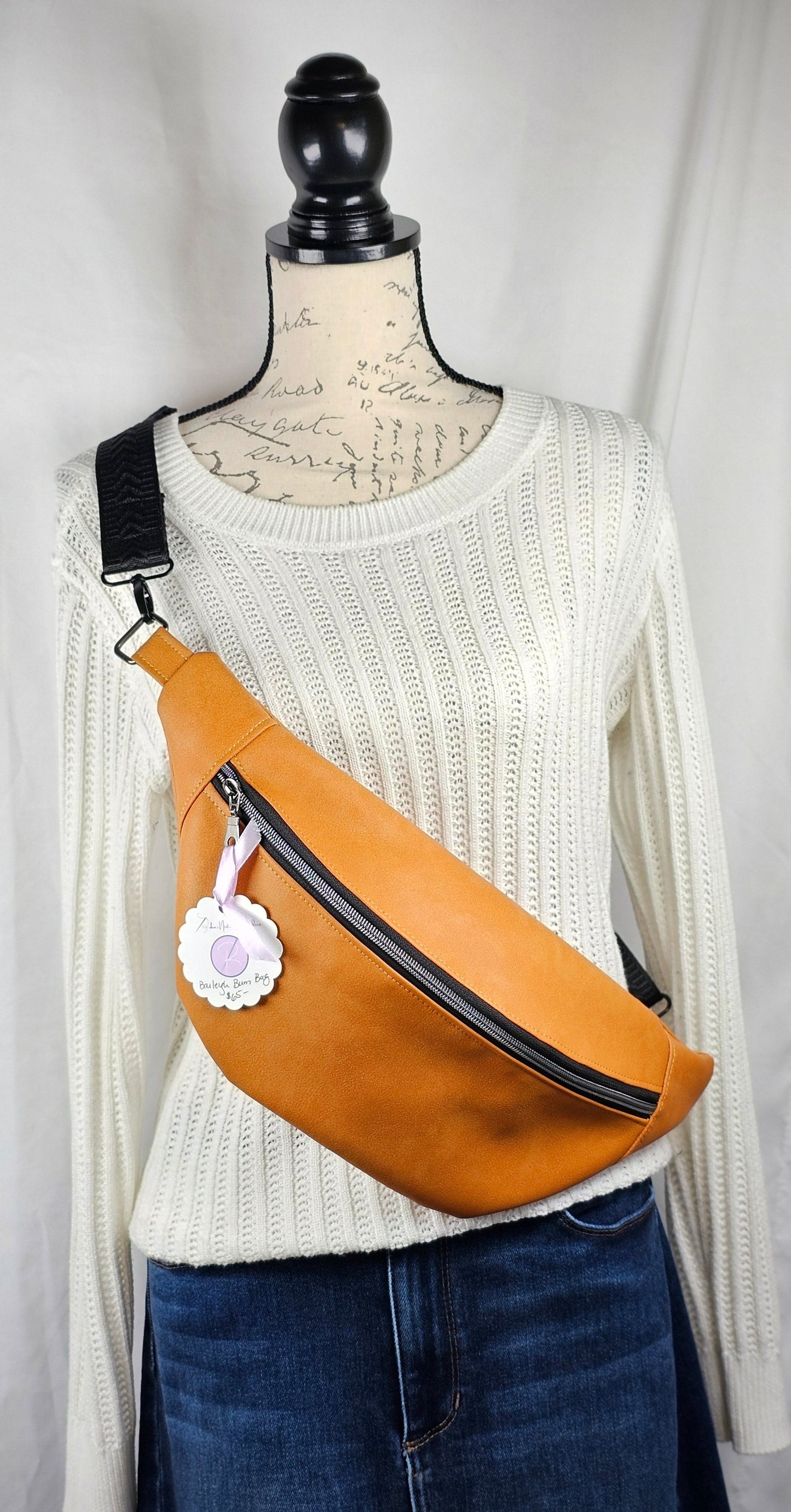 Tan faux leather bum bag, sling bag with fun cat ug cotton lining, black textured strap, with interior zippered and slip pockets.