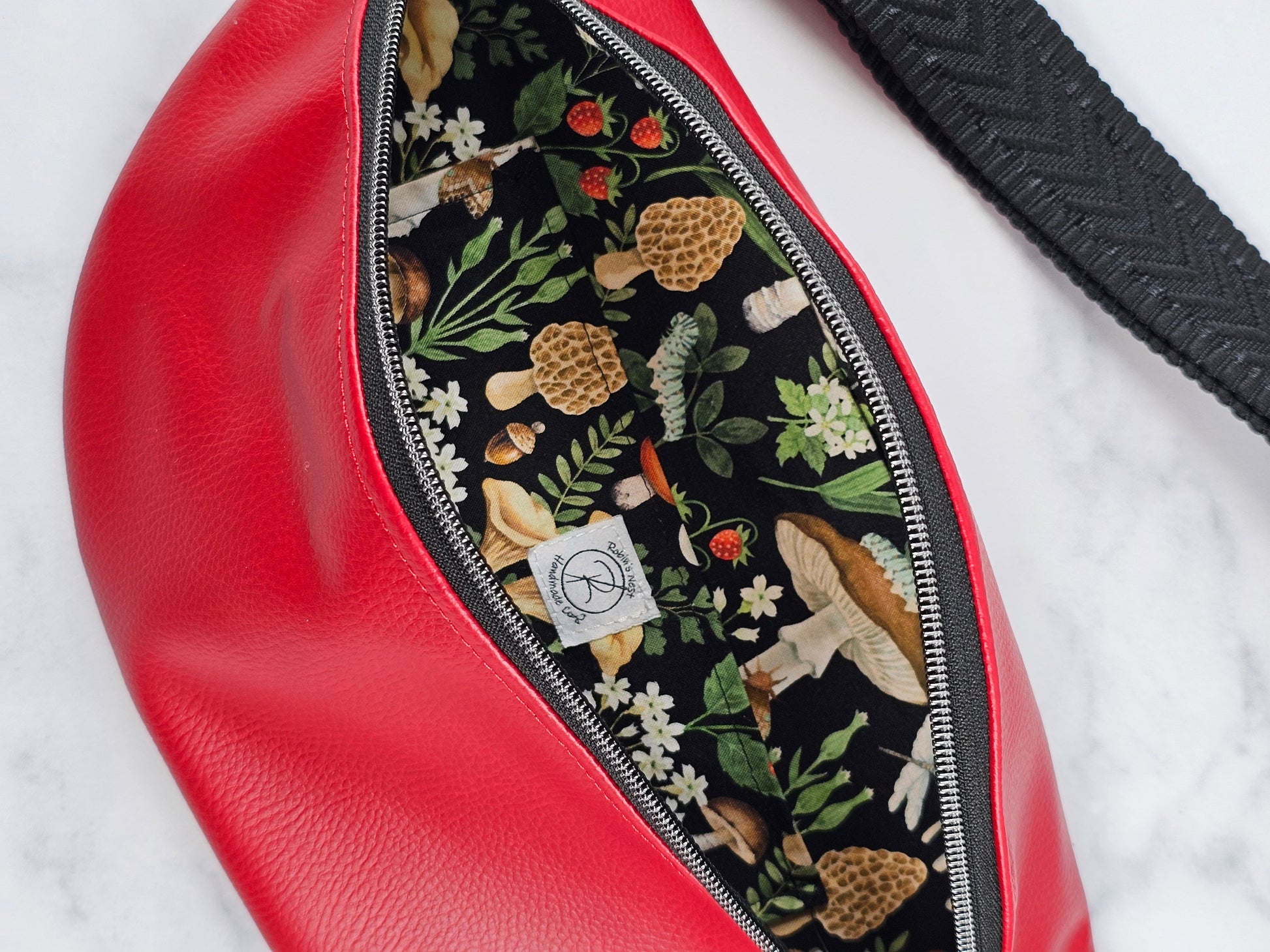 Red faux leather sling fanny pack with mushroom cotton lining and one slip pocket