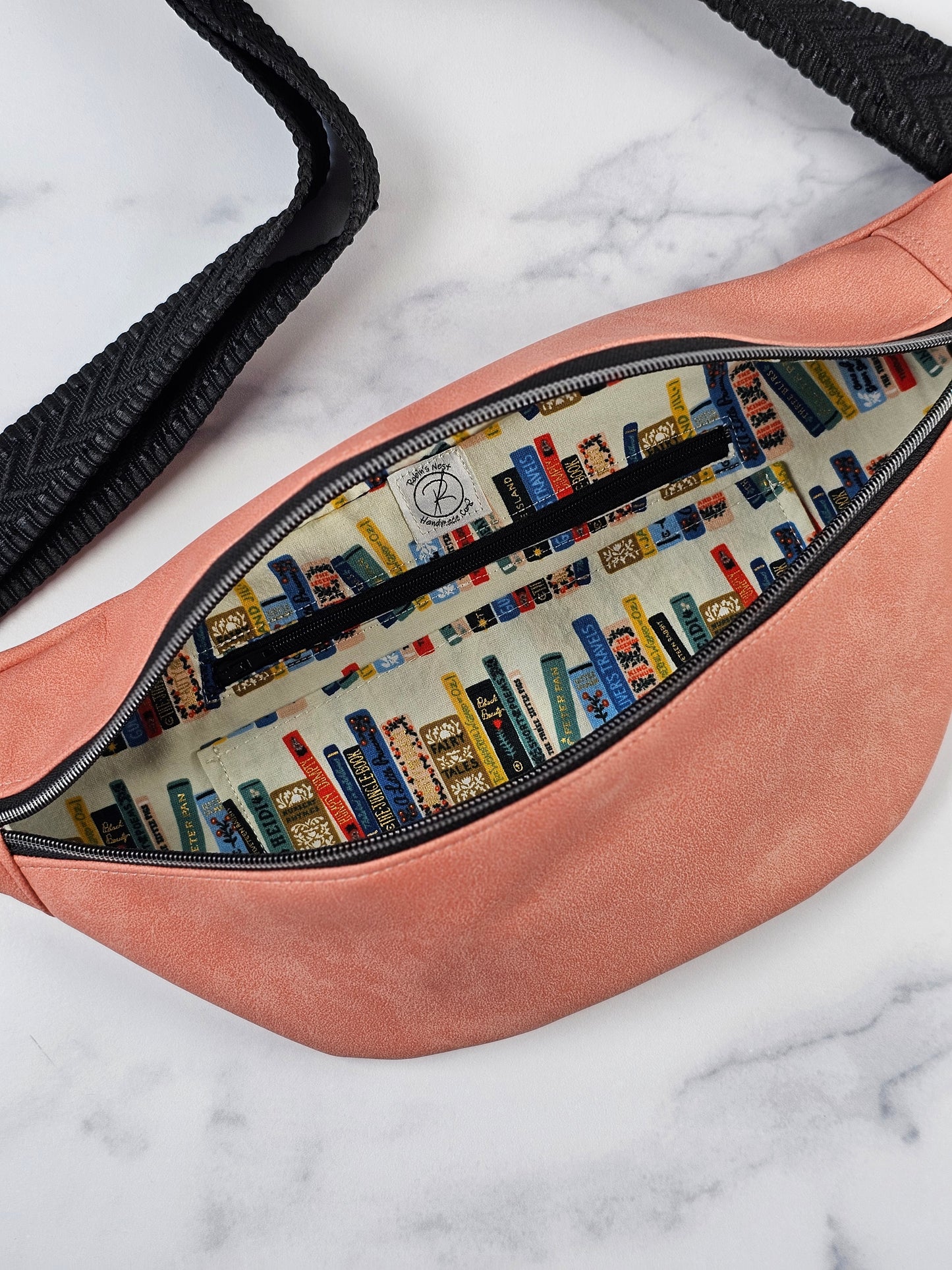 Close-up of a pink bag with a book-themed interior and black accents