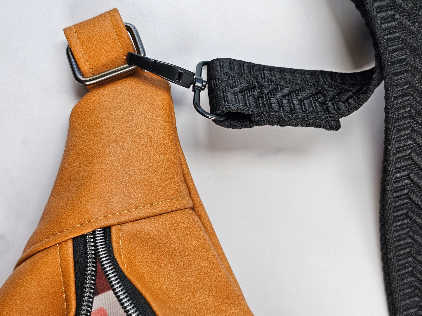 Tan faux leather bum bag, sling bag with fun cat ug cotton lining, black textured strap, with interior zippered and slip pockets.