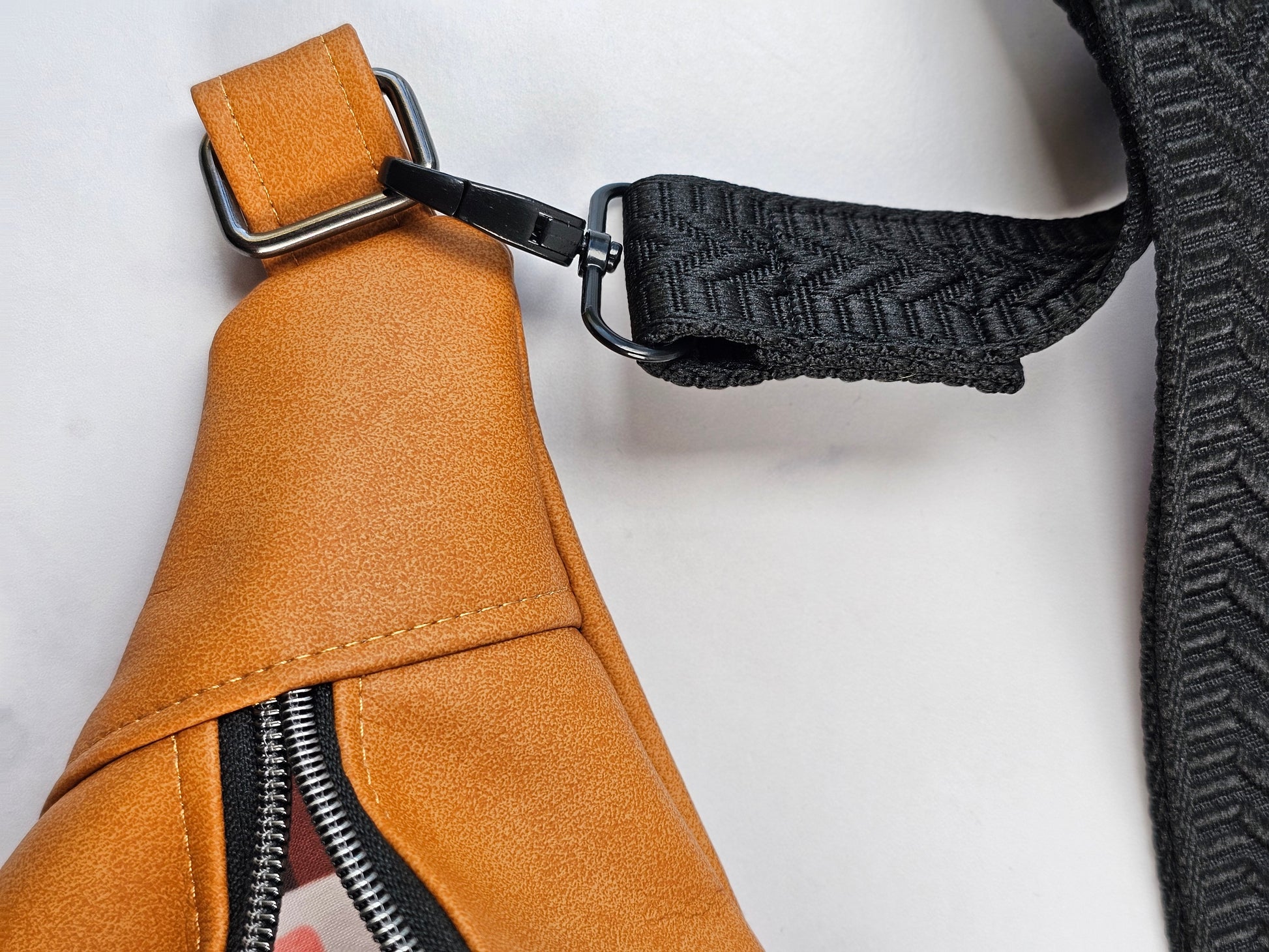 Tan faux leather bum bag, sling bag with fun cat ug cotton lining, black textured strap, with interior zippered and slip pockets.