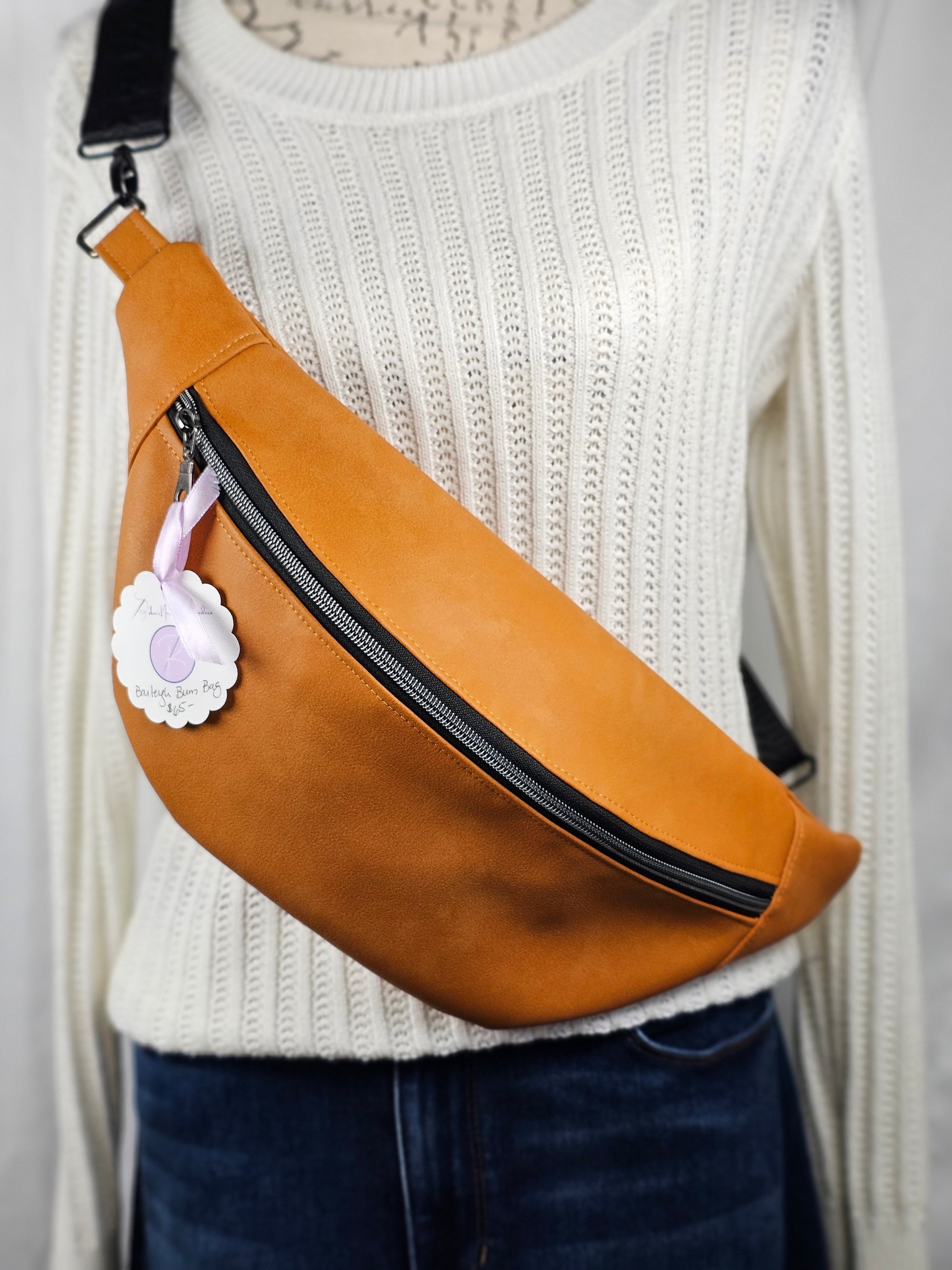 Tan faux leather bum bag, sling bag with fun cat ug cotton lining, black textured strap, with interior zippered and slip pockets.